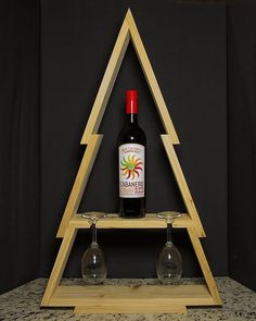 a bottle of wine sitting on top of a wooden shelf next to two wine glasses