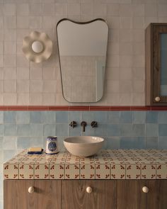 a bathroom with a sink, mirror and tiled counter top in the middle of it