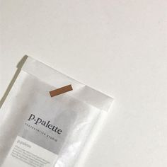 a piece of white paper with a brown stick sticking out of it's side