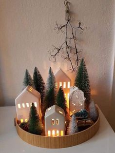 a wooden tray filled with small christmas trees and lit houses on top of a table