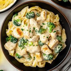 pasta with chicken and broccoli served in a black bowl on a white table