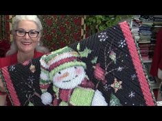 an older woman holding up a christmas themed quilt