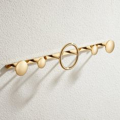 a gold coat rack with three balls on the top and two rings on the bottom