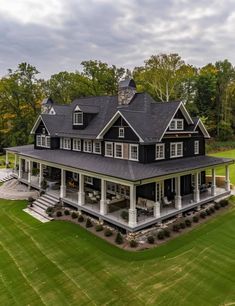 an aerial view of a large black and white house in the middle of a green field