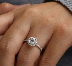 a woman's hand with a diamond ring on her left hand and the other hand holding an engagement ring