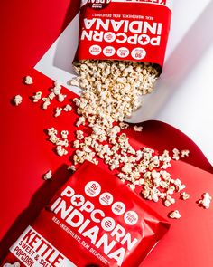 two bags of popcorn sitting on top of a red table next to a bag of popcorn