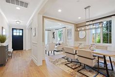 a dining room table and chairs in front of an open living area with hardwood floors