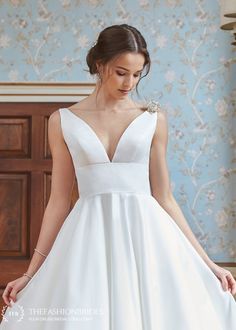 a woman in a white wedding dress standing next to a wall