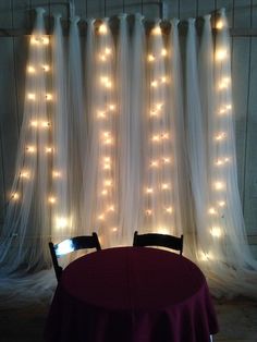 there is a table with a red cloth on it and lights hanging from the curtain