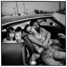 black and white photograph of children in car with man holding child up to his face