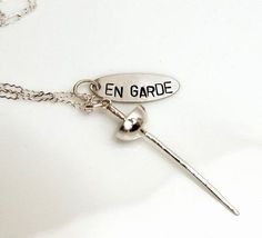 a silver key with the word en garde hanging from it's end on a chain