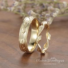 two gold wedding rings sitting on top of a wooden table