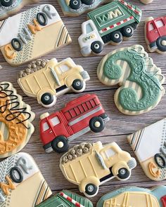 decorated cookies with cars and trucks are on a wooden table next to the cookie cutters