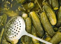 cucumbers being cooked in a pot with a strainer