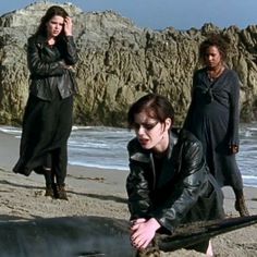 three women are on the beach with an animal in front of them and one woman is holding her head