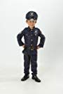 a little boy dressed in police gear standing with his hands on his hips and looking at the camera