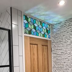 a bathroom with a wooden door next to a white wall and tiled walls behind it