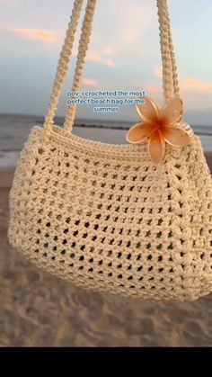 a crocheted purse with a flower hanging from it's side on the beach