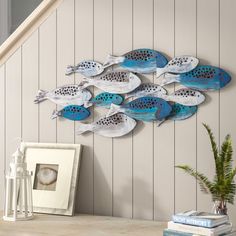 a group of blue and white fish mounted to the side of a wall next to a potted plant