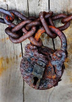 an old rusted padlock is attached to a wooden fence with chains and locks