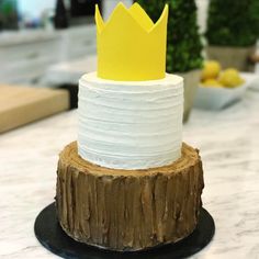 a cake that is sitting on top of a tree stump with a crown on it