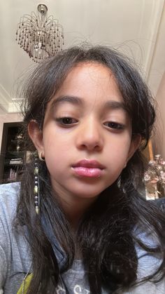 a close up of a person with long hair and earrings on her head, looking at the camera