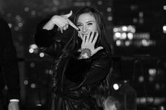 black and white photograph of a woman holding her hand up to her mouth with the city lights in the background