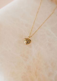 This delicate necklace features a scattering of sparkling CZ gems across a small heart pendant hanging on a dainty gold cable chain, making it the perfect accessory for any occasion. Adjustable 16-18" in length 12mm x 12mm amulet (approx) Heavy 18k Gold Plate over brass with e-coating for extra longevity ** Our pieces are plated 1 micron thick, industry standard is .125. Quality & longevity are extremely important to us. We wanted to ensure these pieces will last and work well for sensitive skin Gold Heart Charm Necklaces, Gold Heart Charm Necklaces With Heart Cut, Gold Heart Cut Charm Necklace, Delicate Gold Heart Charm Necklace, Delicate Tiny Gold Heart Necklace, Dainty Tiny Gold Heart Necklace, Delicate Gold Charm Necklaces With Heart Pendant, Delicate Gold Heart Pendant Charm Necklaces, Delicate Gold Charm Necklace With Heart Pendant