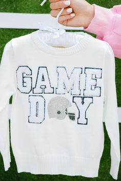 Little ones will love showing their team spirit with our Mini Kids Game Day White Sweater. Made of soft knit material, this sweater features a small white varsity "Game Day" letter and a shiny silver rhinestone helmet patch. Perfect for keeping warm and stylish during games or everyday wear. Go team! All orders are currently shipping within 14 business days. To receive item quicker, expedited shipping is available at checkout. Go Team, Kids Game, How To Show Love, White Sweater, Silver Rhinestone, Shiny Silver, Knitting Materials, White Sweaters, Team Spirit