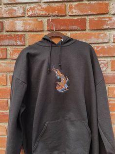 "Koi Fish Embroidered Hoodie -Embroidered on a cotton/polyester blend hoodie, this design is simple and minimalistic, perfect for every outfit! -Embroidery design measures 6\" x 3\" -See product pictures for shirt sizing chart. -Hanes/Gildan Brand depending on availability. -All sweatshirts are handmade on an embroidery machine so there may be slight differences, but we only sell the shirts that meet our high-quality standards. -To maintain the quality of your shirt and the embroidery design mak Embroidered Hoodie For Fall Streetwear, Embroidered Black Hoodie For Fall, Black Embroidered Hoodie For Fall, Black Hoodie With Embroidered Graphics For Fall, Black Embroidered Hooded Hoodie, Embroidered Black Hoodie For Streetwear, Black Casual Hoodie With Embroidered Graphics, Black Embroidered Hoodie For Streetwear, Black Embroidered Long Sleeve Hoodie