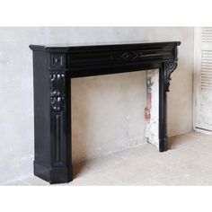 an antique black fireplace mantel with ornate carvings on the top and sides, in front of a white wall