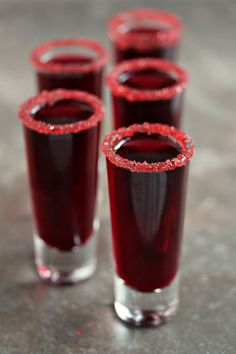 four glasses filled with liquid sitting on top of a table