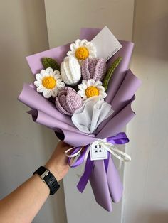 a person holding a bouquet of crocheted flowers in their left hand with the tag on it