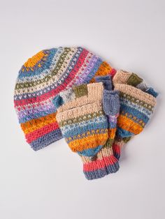 two knitted mittens sitting next to each other on top of a white surface