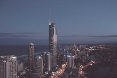 an aerial view of a city at night with skyscrapers lit up and the ocean in the background