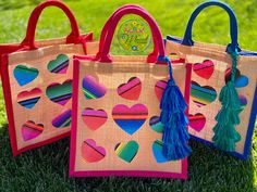 three bags with hearts and tassels are on the grass