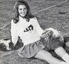 a woman sitting on the ground with her legs crossed and wearing a cheerleader outfit