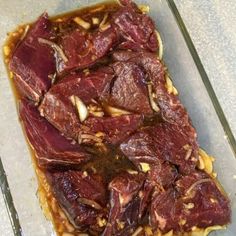 raw meat is sitting in a baking dish on a counter top, ready to be put into the oven