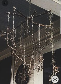 an outdoor chandelier made out of branches and twigs hanging from the side of a house