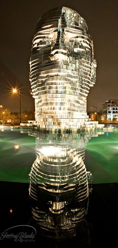 an artistic sculpture is shown in front of a cityscape at night with lights shining on it