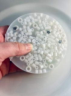 a person is holding some white beads in their left hand and pointing at them on the other side