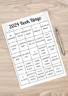 the printable book bingo is on top of a wooden table next to a pen