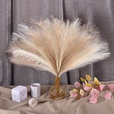 a vase with some flowers and candles on a table next to a cloth covered backdrop