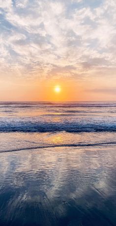 the sun is setting over the ocean with clouds in the sky and water reflecting on the wet sand