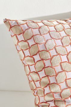 an orange and white pillow sitting on top of a bed