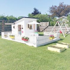 a small white house sitting on top of a lush green field next to a wooden fence