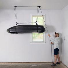 a man standing next to a black boat suspended from the ceiling