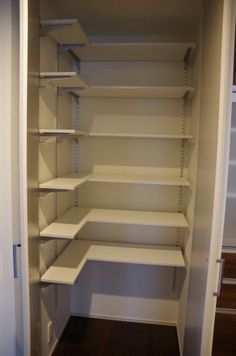 an empty walk in closet with white shelves