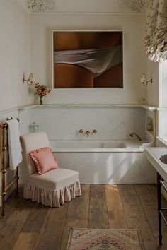 a bath room with a tub a sink and a painting on the wall above it