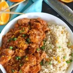 a white bowl filled with rice and meat next to an orange slice on the side